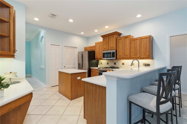 6619 Pinefeather Ct, Bradenton, FL 34203 - kitchen featuring stainless steel appliances, a center island, brown cabinets, light tile patterned floors, and recessed lighting
