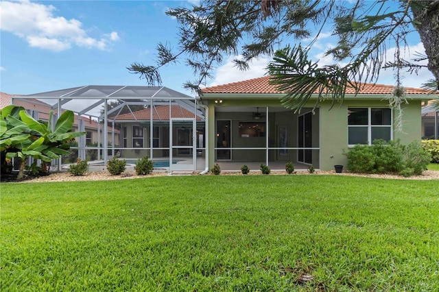 6619 Pinefeather Ct, Bradenton, FL 34203 - back of house featuring a yard, a ceiling fan, stucco siding, a tiled roof, and glass enclosure