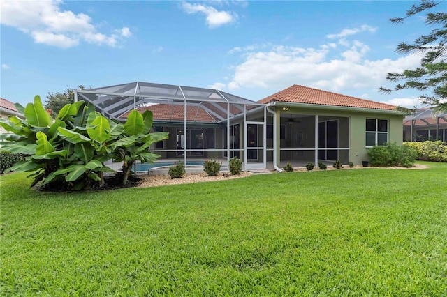 6619 Pinefeather Ct, Bradenton, FL 34203 - rear view of property with a yard, a tiled roof, a ceiling fan, glass enclosure, and stucco siding