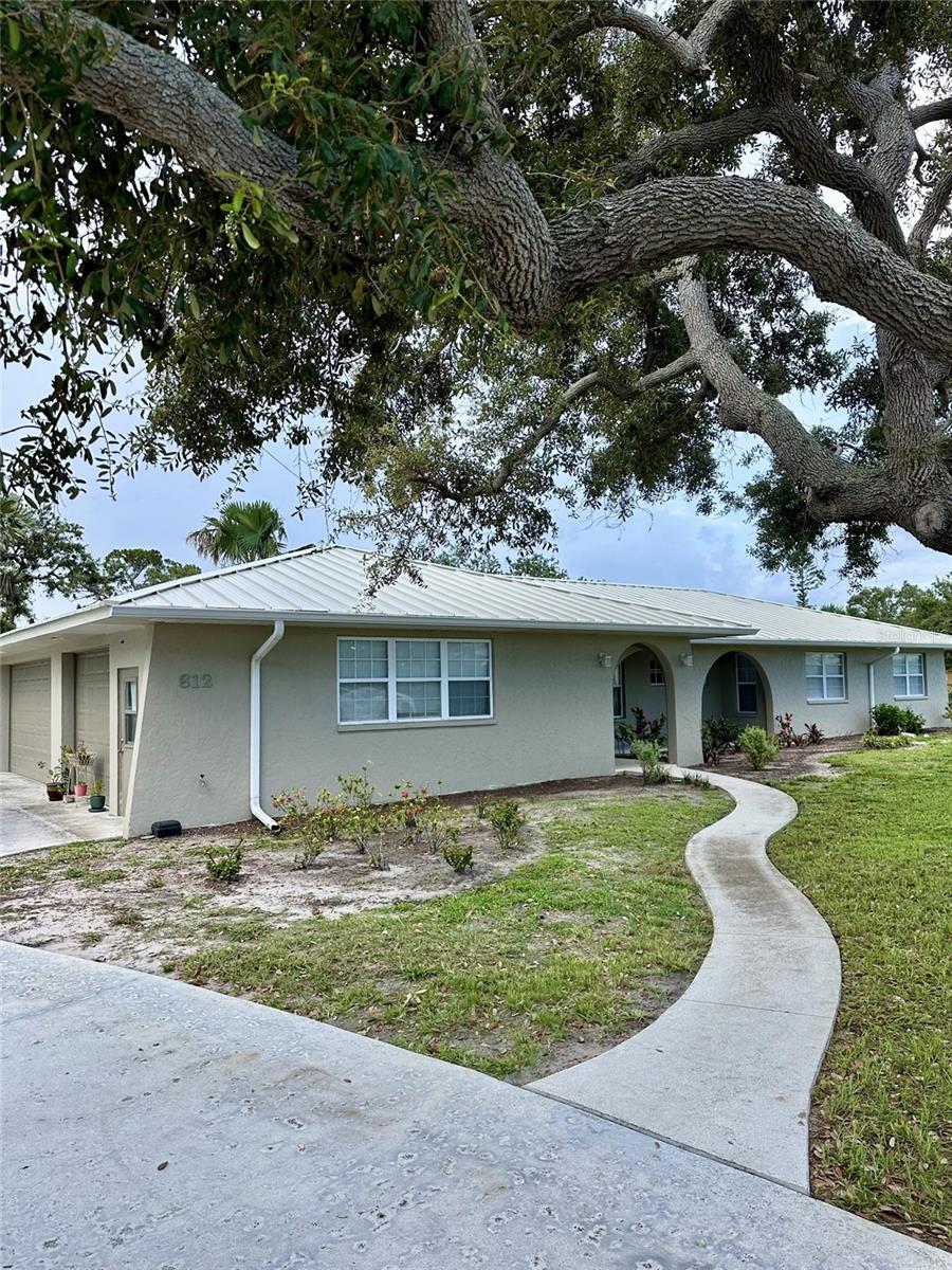 612 Bayshore Rd, Nokomis, FL 34275 - ranch-style home featuring stucco siding, a front yard, a metal roof, a garage, and concrete driveway