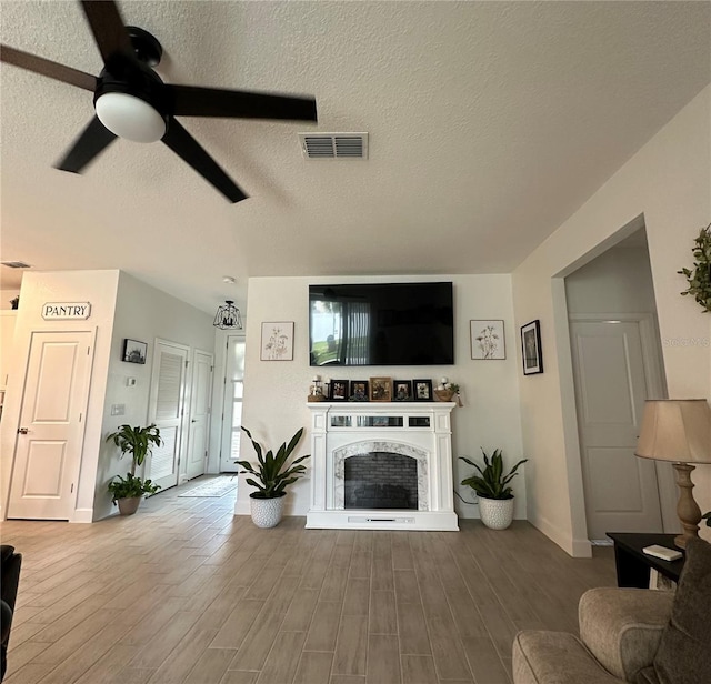 4033 Union Ln, North Port, FL 34288 - living room with a ceiling fan, wood finished floors, a textured ceiling, and a high end fireplace