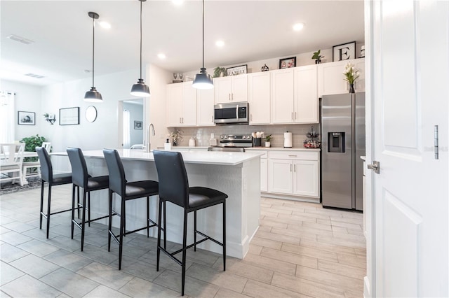 4033 Union Ln, North Port, FL 34288 - kitchen featuring stainless steel appliances, decorative backsplash, light countertops, a center island with sink, and a kitchen breakfast bar