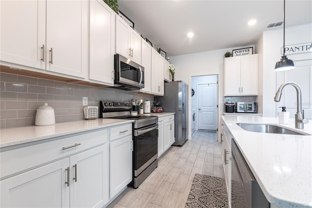 4033 Union Ln, North Port, FL 34288 - kitchen with stainless steel appliances, backsplash, white cabinets, decorative light fixtures, and light stone countertops