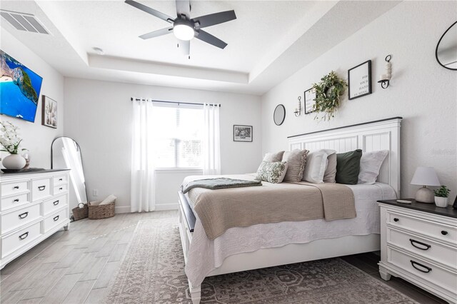 4033 Union Ln, North Port, FL 34288 - bedroom featuring a tray ceiling, light wood-type flooring, and a ceiling fan