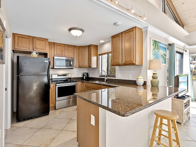 500 Park Blvd S Unit 33, Venice, FL 34285 - kitchen featuring stainless steel appliances, a peninsula, light tile patterned flooring, dark stone counters, and a breakfast bar area