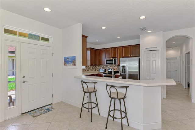 371 Capulet Dr, Venice, FL 34292 - kitchen featuring stainless steel appliances, a kitchen bar, light tile patterned flooring, backsplash, and recessed lighting