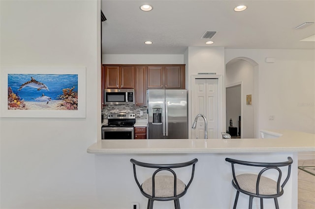 371 Capulet Dr, Venice, FL 34292 - kitchen with stainless steel appliances, a breakfast bar, light countertops, backsplash, and recessed lighting