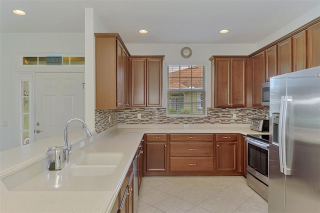 371 Capulet Dr, Venice, FL 34292 - kitchen featuring appliances with stainless steel finishes, light countertops, light tile patterned flooring, tasteful backsplash, and a peninsula