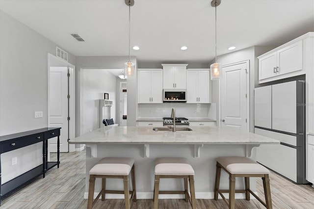 11240 Spring Gate Trl, Bradenton, FL 34211 - kitchen with white appliances, light wood-style floors, white cabinetry, tasteful backsplash, and a breakfast bar