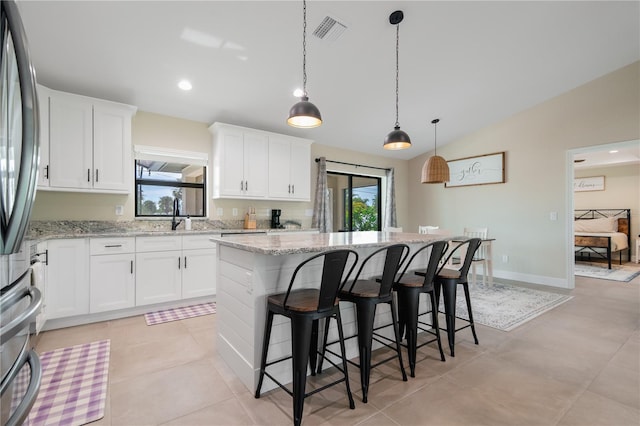 7257 Maguire Ln, Englewood, FL 34224 - kitchen with a center island, plenty of natural light, freestanding refrigerator, a kitchen bar, and lofted ceiling