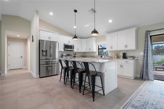 7257 Maguire Ln, Englewood, FL 34224 - kitchen featuring stainless steel appliances, healthy amount of natural light, a breakfast bar, white cabinets, and vaulted ceiling