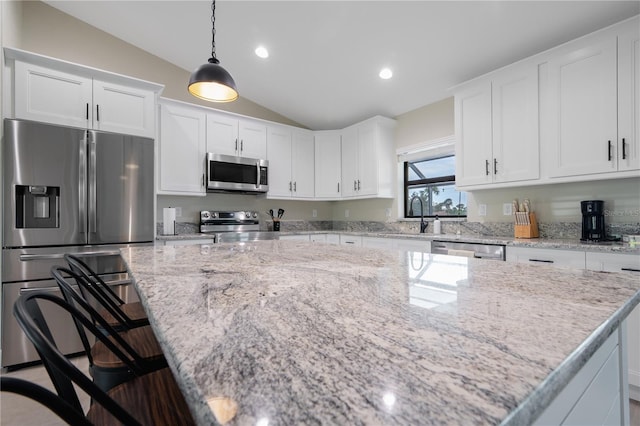 7257 Maguire Ln, Englewood, FL 34224 - kitchen featuring stainless steel appliances, vaulted ceiling, white cabinetry, hanging light fixtures, and a kitchen island