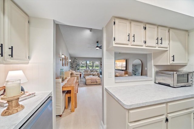 1211 Capri Isles Blvd Unit 6, Venice, FL 34292 - kitchen with a ceiling fan, light countertops, light wood-style flooring, white cabinetry, and vaulted ceiling