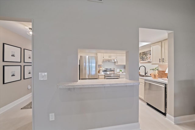 1211 Capri Isles Blvd Unit 6, Venice, FL 34292 - kitchen featuring stainless steel appliances, under cabinet range hood, light countertops, white cabinetry, and a peninsula