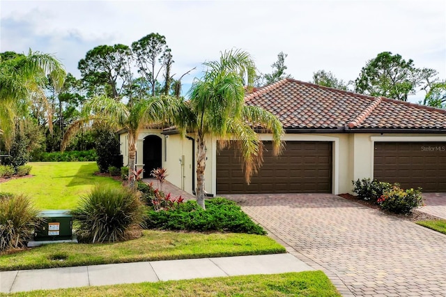 12187 Amica Loop, Venice, FL 34293 - mediterranean / spanish home featuring a garage, decorative driveway, stucco siding, and a front yard