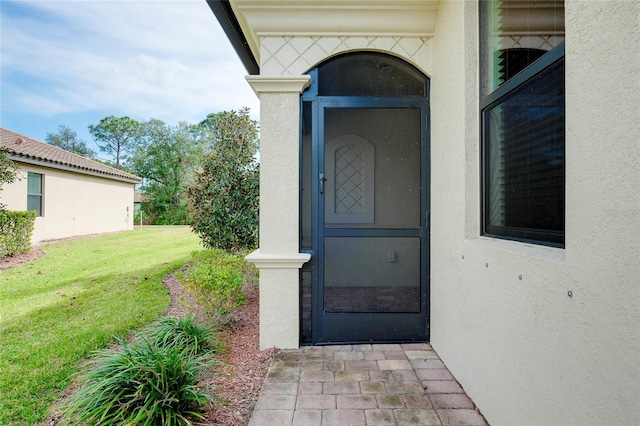 12187 Amica Loop, Venice, FL 34293 - view of exterior entry featuring a lawn and stucco siding