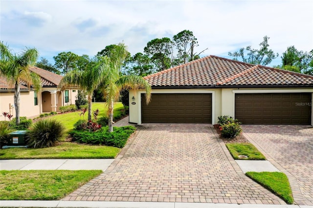 12187 Amica Loop, Venice, FL 34293 - mediterranean / spanish-style home with a garage, driveway, stucco siding, a front yard, and a tile roof