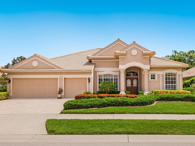 355 Swallow Cir, Venice, FL 34285 - mediterranean / spanish home featuring an attached garage, driveway, stucco siding, and a tile roof