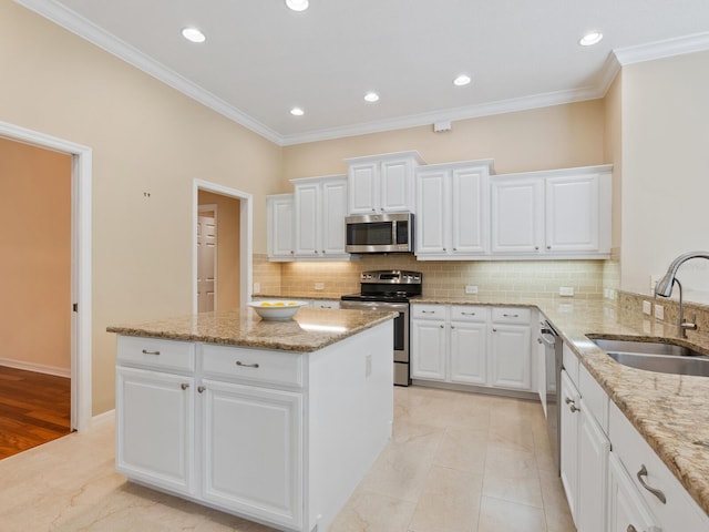 355 Swallow Cir, Venice, FL 34285 - kitchen with appliances with stainless steel finishes, a center island, backsplash, white cabinetry, and crown molding