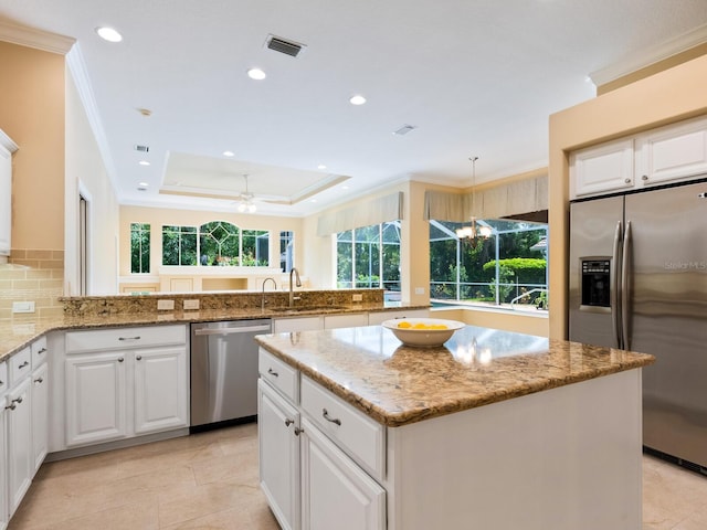 355 Swallow Cir, Venice, FL 34285 - kitchen featuring appliances with stainless steel finishes, light stone countertops, a kitchen island, a peninsula, and crown molding