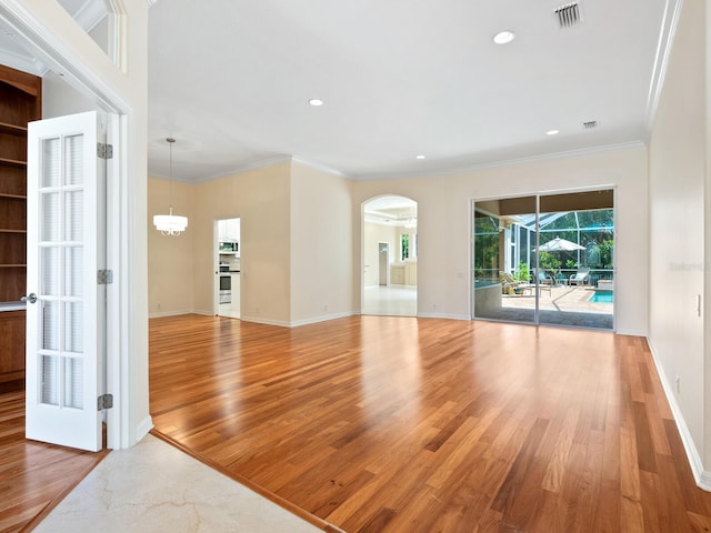 355 Swallow Cir, Venice, FL 34285 - spare room with arched walkways, light wood-style flooring, recessed lighting, and crown molding