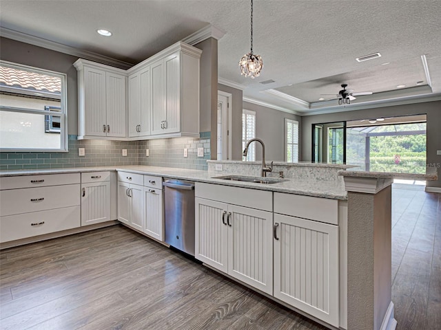 5832 Semolino St, Nokomis, FL 34275 - kitchen with stainless steel dishwasher, crown molding, a peninsula, wood finished floors, and white cabinetry