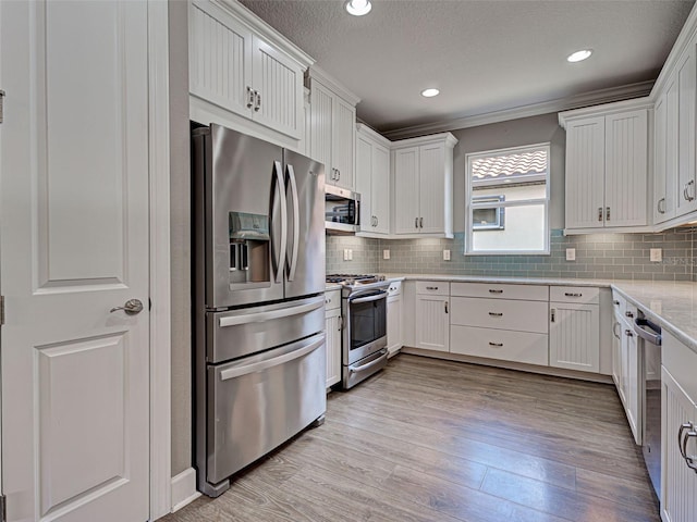 5832 Semolino St, Nokomis, FL 34275 - kitchen featuring appliances with stainless steel finishes, light wood-type flooring, decorative backsplash, white cabinets, and recessed lighting