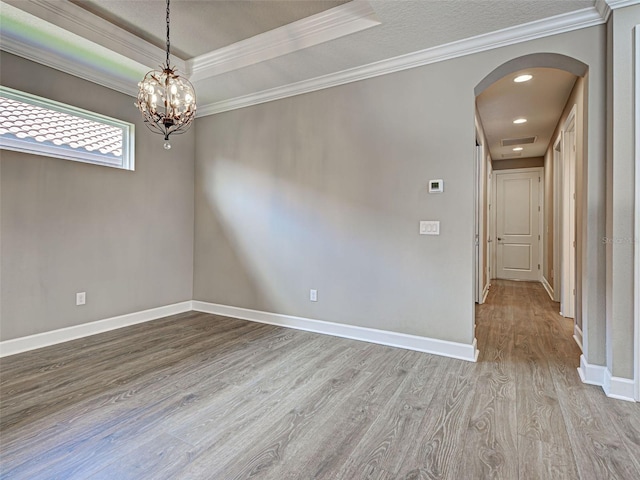 5832 Semolino St, Nokomis, FL 34275 - empty room with arched walkways, wood finished floors, a tray ceiling, ornamental molding, and a chandelier