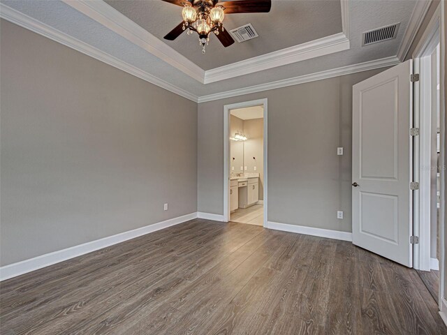 5832 Semolino St, Nokomis, FL 34275 - unfurnished bedroom featuring a tray ceiling, wood finished floors, crown molding, connected bathroom, and ceiling fan