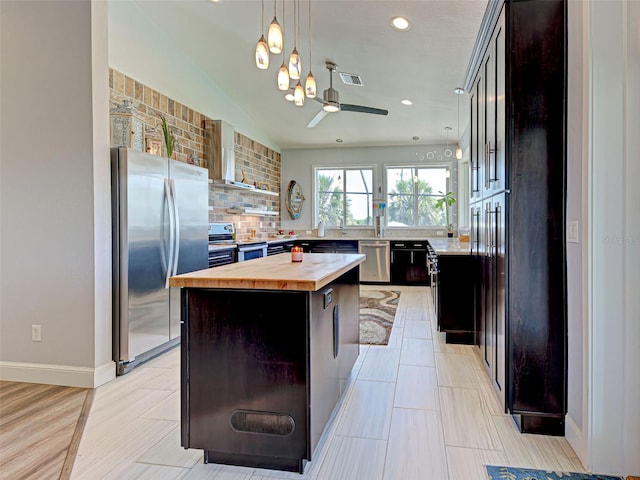 48 Lark Dr, Placida, FL 33946 - kitchen with wood counters, stainless steel appliances, wall chimney range hood, decorative backsplash, and a center island