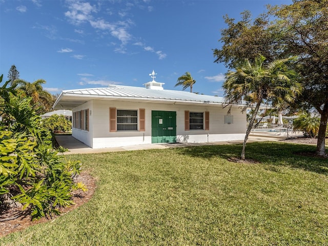 168 The Corso Unit 168, Venice, FL 34285 - back of property featuring concrete block siding, a lawn, a metal roof, and a standing seam roof