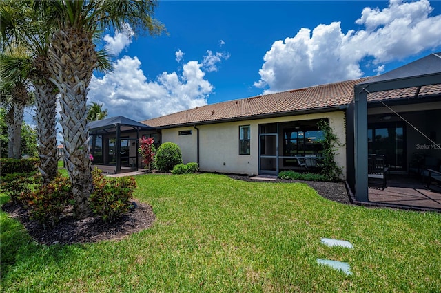 19269 Serafina St, Venice, FL 34293 - rear view of property featuring a tile roof, stucco siding, a lawn, a lanai, and a patio