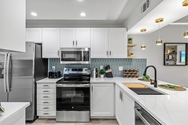 437 Cerromar Ln Unit 424, Venice, FL 34293 - kitchen featuring stainless steel appliances, white cabinetry, tasteful backsplash, decorative light fixtures, and light stone counters