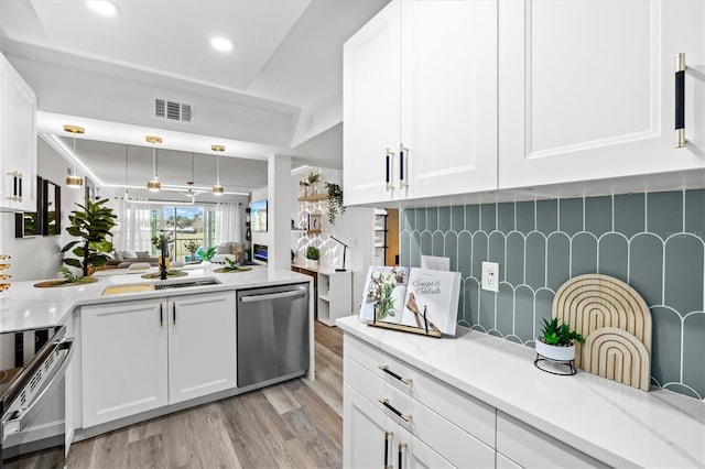 437 Cerromar Ln Unit 424, Venice, FL 34293 - kitchen with stainless steel appliances, light wood finished floors, white cabinetry, backsplash, and hanging light fixtures