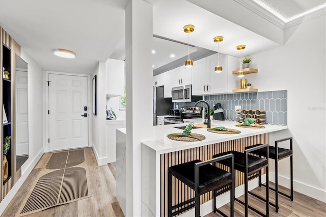 437 Cerromar Ln Unit 424, Venice, FL 34293 - kitchen featuring stainless steel appliances, light countertops, white cabinetry, a kitchen bar, and decorative backsplash