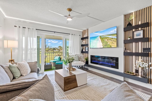 437 Cerromar Ln Unit 424, Venice, FL 34293 - living area featuring a textured ceiling, a glass covered fireplace, a ceiling fan, and wood finished floors