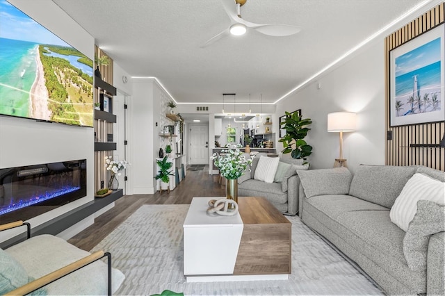437 Cerromar Ln Unit 424, Venice, FL 34293 - living area featuring a ceiling fan, wood finished floors, a glass covered fireplace, and a textured ceiling