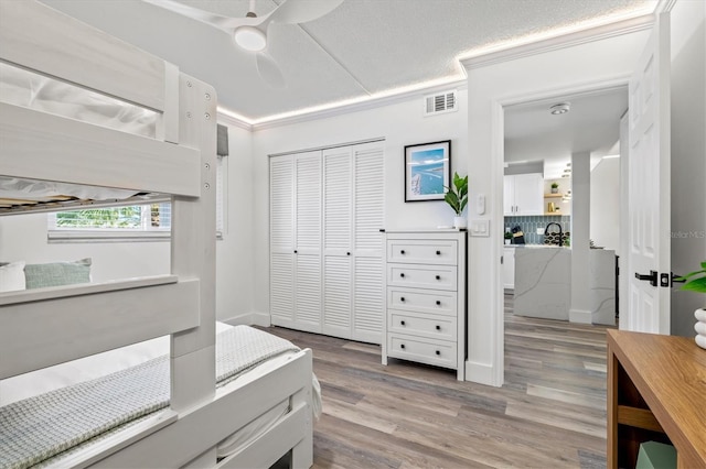 437 Cerromar Ln Unit 424, Venice, FL 34293 - bedroom featuring a closet, light wood-type flooring, a ceiling fan, and ornamental molding