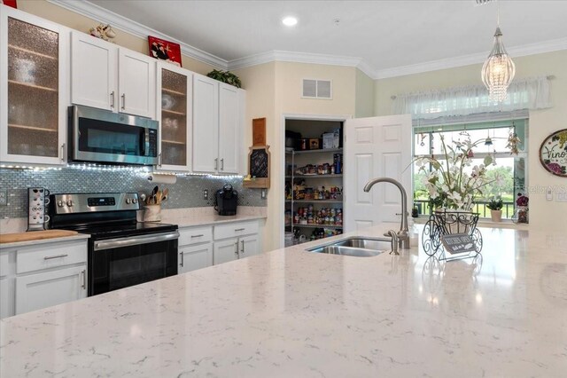 935 Tidewater Shrs Unit 721, Bradenton, FL 34208 - kitchen featuring appliances with stainless steel finishes, ornamental molding, decorative backsplash, white cabinetry, and pendant lighting