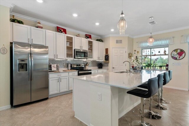 935 Tidewater Shrs Unit 721, Bradenton, FL 34208 - kitchen with appliances with stainless steel finishes, backsplash, white cabinets, a kitchen breakfast bar, and hanging light fixtures