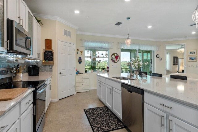 935 Tidewater Shrs Unit 721, Bradenton, FL 34208 - kitchen featuring stainless steel appliances, crown molding, white cabinets, backsplash, and light stone counters