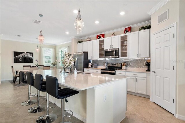935 Tidewater Shrs Unit 721, Bradenton, FL 34208 - kitchen featuring stainless steel appliances, decorative backsplash, a kitchen breakfast bar, ornamental molding, and white cabinetry