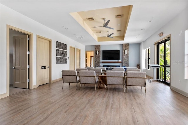 935 Tidewater Shrs Unit 721, Bradenton, FL 34208 - living room featuring a raised ceiling, light wood-style flooring, a ceiling fan, and a fireplace