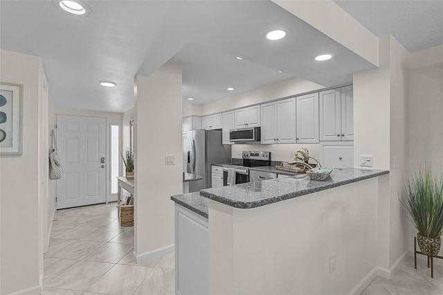 950 Tarpon Center Dr Unit 305, Venice, FL 34285 - kitchen with appliances with stainless steel finishes, dark stone countertops, white cabinetry, a peninsula, and recessed lighting