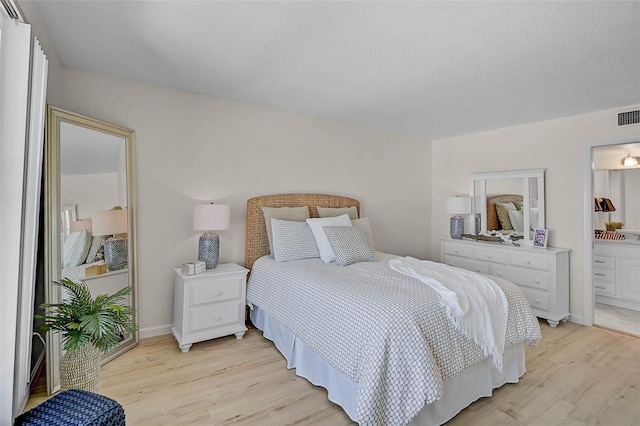 950 Tarpon Center Dr Unit 305, Venice, FL 34285 - bedroom with light wood-style floors, ensuite bathroom, and a textured ceiling