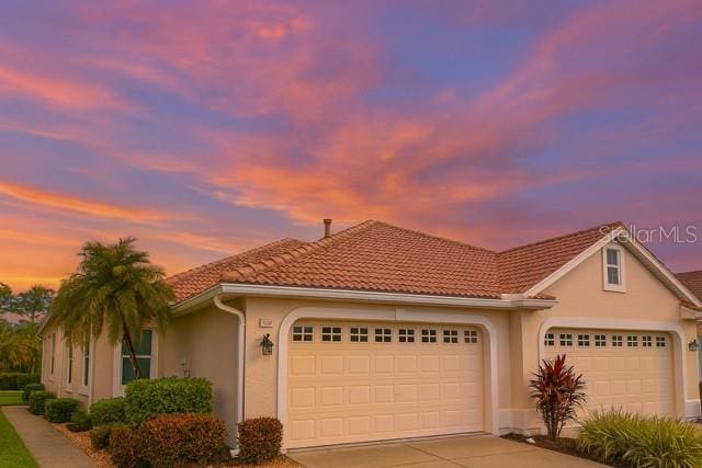 4343 Whispering Oaks Dr, North Port, FL 34287 - view of front of home featuring a garage, concrete driveway, stucco siding, and a tile roof