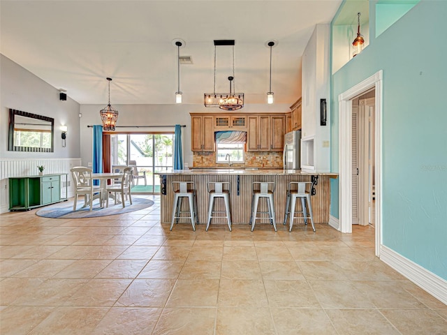 23102 Madelyn Ave, Port Charlotte, FL 33954 - kitchen featuring a chandelier, freestanding refrigerator, brown cabinetry, a kitchen bar, and decorative backsplash