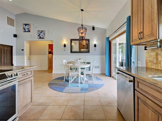 23102 Madelyn Ave, Port Charlotte, FL 33954 - kitchen featuring stainless steel appliances, a wainscoted wall, a chandelier, light stone countertops, and high vaulted ceiling