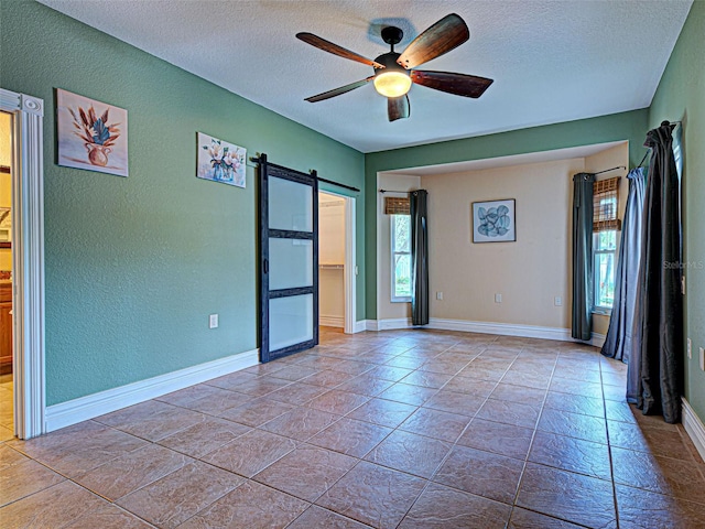 23102 Madelyn Ave, Port Charlotte, FL 33954 - spare room featuring a textured wall, a textured ceiling, a barn door, and a ceiling fan