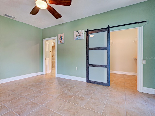 23102 Madelyn Ave, Port Charlotte, FL 33954 - empty room with light tile patterned floors, ceiling fan, and a barn door